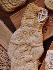 some very pretty looking cookies on a wooden board with carving work around it's edges