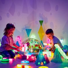 two children playing with colorful lights in a room