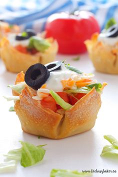 small appetizers with vegetables and black olives on them sitting on a table