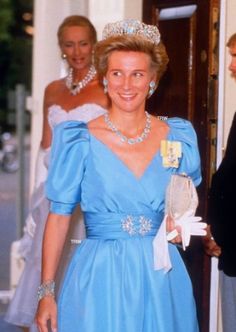 the princess is wearing a blue dress and tiara while standing next to other people