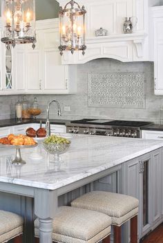 a kitchen island with two stools in front of it and lights hanging from the ceiling