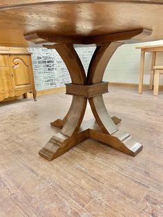 a round wooden table sitting on top of a hard wood floored floor in a room