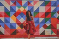 a woman standing in front of a colorful wall