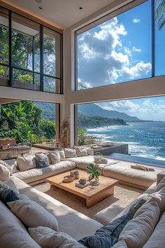 a living room filled with furniture and large windows overlooking the ocean in front of it