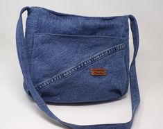 a denim bag with a leather tag on the front and shoulder strap, sitting on a white surface