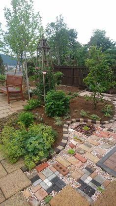 an outdoor garden with brick walkways, trees and plants in the middle of it