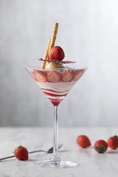 a dessert in a martini glass with strawberries on the rim