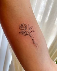 a woman's arm with a small flower tattoo on the left side of her arm