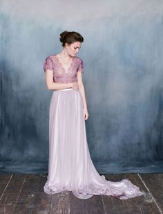 a woman standing in front of a blue wall wearing a dress with sheer lace on it