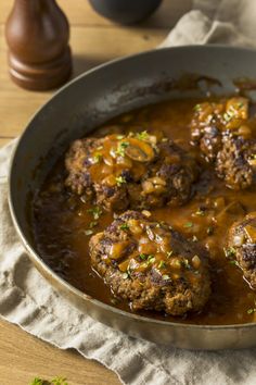 meatballs covered in gravy sit in a skillet on a wooden table