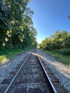 an empty train track with trees in the background