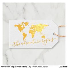 a white and gold tag with the words adventure begins world map - by paper grape travel