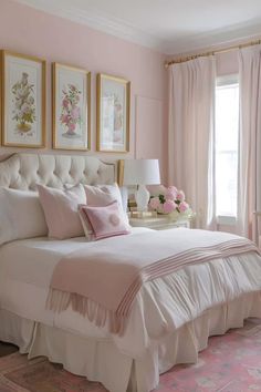 a bedroom with pink walls and white bedding, framed pictures on the wall above it