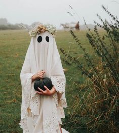 a woman dressed as a ghost holding a black ball