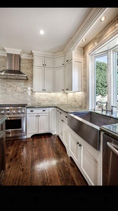 a kitchen with white cabinets and wood floors, stainless steel sink and dishwasher