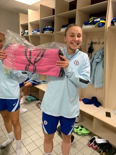 two girls in the locker room holding up a pink bag