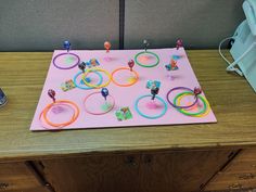 a pink table topped with lots of different colored bracelets and rings on top of it