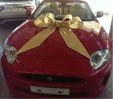 a red sports car with a yellow bow on the hood