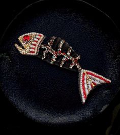 a black plate topped with a red, white and blue fish brooch