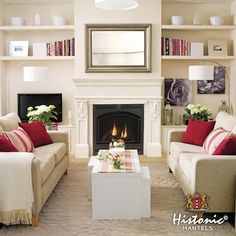 a living room with two couches and a fire place in the center, surrounded by bookshelves