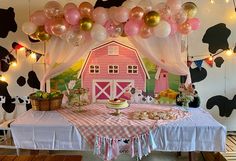 a farm themed birthday party with balloons, cake and desserts on a table in front of a barn backdrop