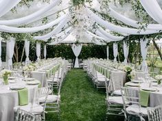 an outdoor wedding venue with white drapes and green linens on the tables set up