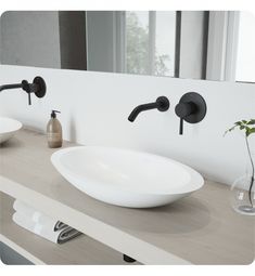 a white bowl sink sitting on top of a counter next to two black faucets