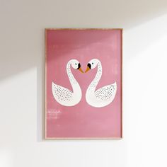 two white swans in a pink frame hanging on the wall