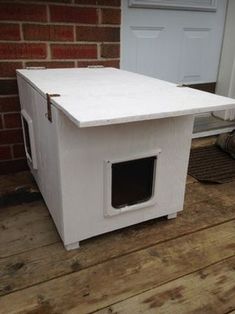 a white dog house sitting on top of a wooden floor next to a brick wall