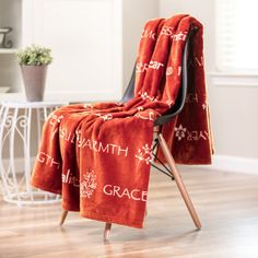 a chair covered in a red towel with the words grace printed on it and a potted plant next to it