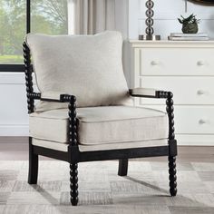 a white chair sitting on top of a wooden floor next to a dresser and window