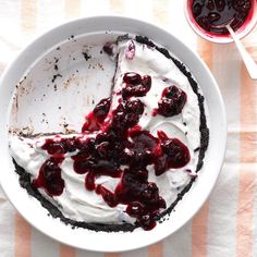 a white plate topped with a pie covered in whipped cream and cherries