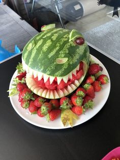 a watermelon carved to look like a shark's mouth with strawberries on the bottom