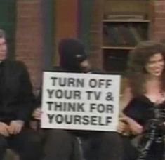 a woman holding a sign that says turn off your tv and think for yourself with two men in the background