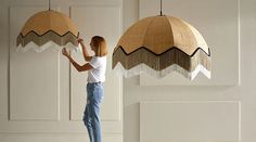 a woman is painting the ceiling in front of two hanging lights that look like mountains