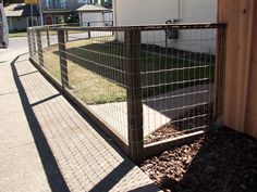 a metal fence on the side of a road next to a building with a house in the background