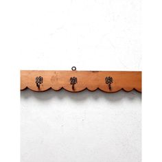 three wooden hooks hang from the side of a wall with scalloped edges and metal knobs