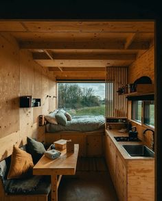 the interior of a tiny cabin with wooden walls and flooring, including a kitchen area