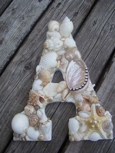 a letter made out of seashells on a wooden surface