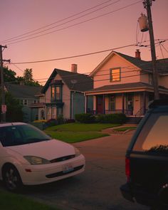 a white car parked on the side of a road next to a house at sunset