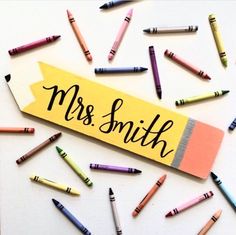 some crayons are scattered around a wooden sign that says,'mrs smith '