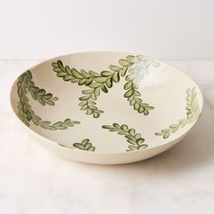 a white bowl with green leaves painted on it