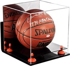 two basketballs in a clear case with orange cones on the bottom and black base