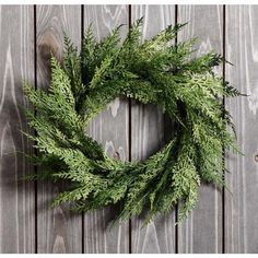 a green wreath hanging on a wooden wall