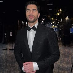 a man in a tuxedo is posing for a photo at an event with his hands in his pockets