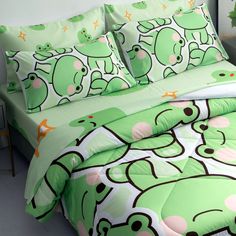 a bed with green frog comforters and pillows on top of it next to a potted plant