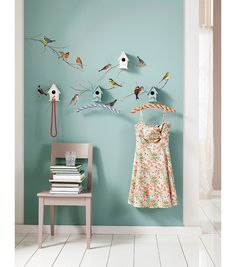 there are many birds hanging on the wall next to a dress and birdhouses