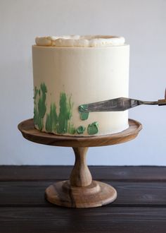 a white cake with green icing and a knife stuck in the frosting on top