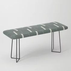 a green bench sitting on top of a black metal frame stand next to a white wall