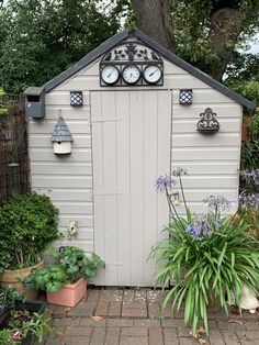 a garden shed with two clocks on the roof